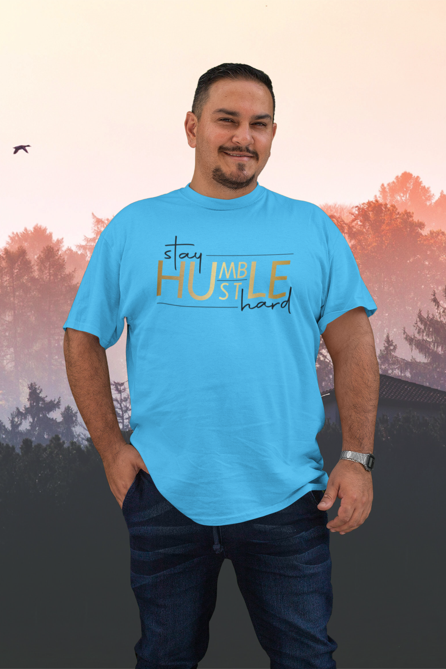 A man wearing a blue shirt with a lettering colors in gold and black saying: Stay humble, hustle hard