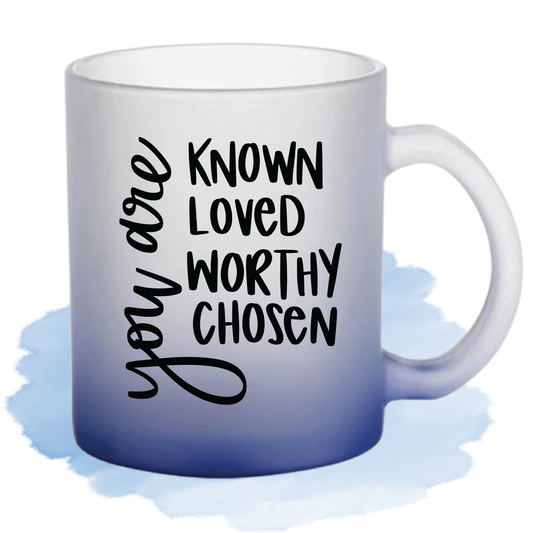 A blue gradient glass mug with a black lettering saying "You are known, loved, worthy, chosen,